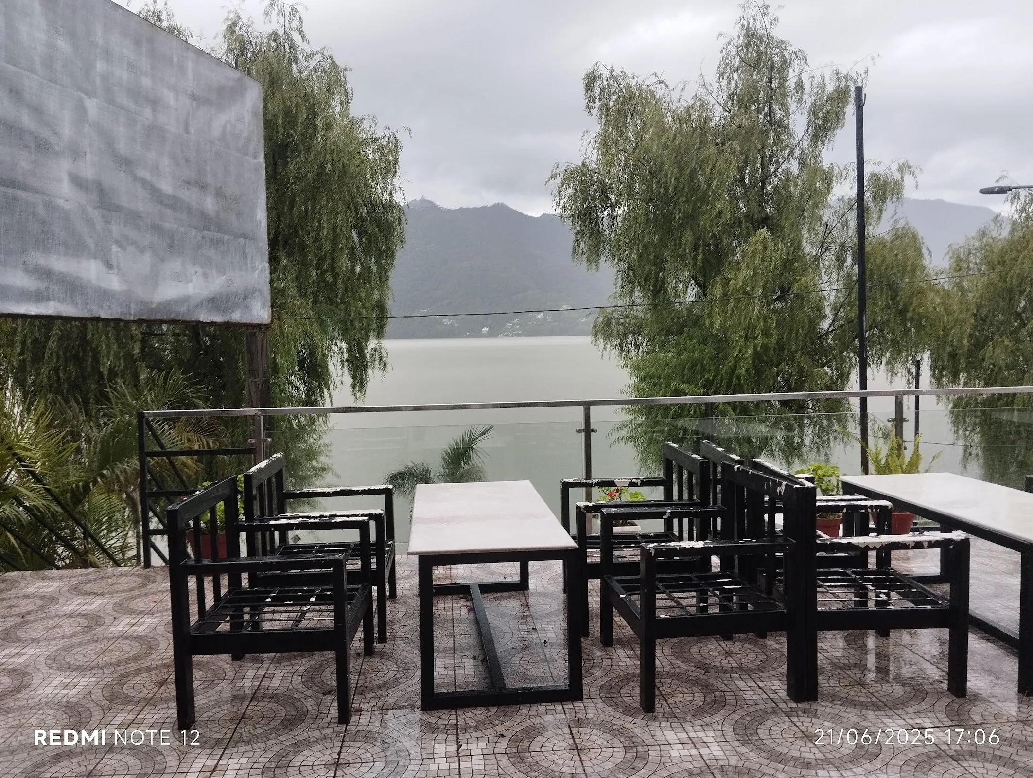 Outdoor lakeside seating under willow trees with chairs facing Fewa Lake