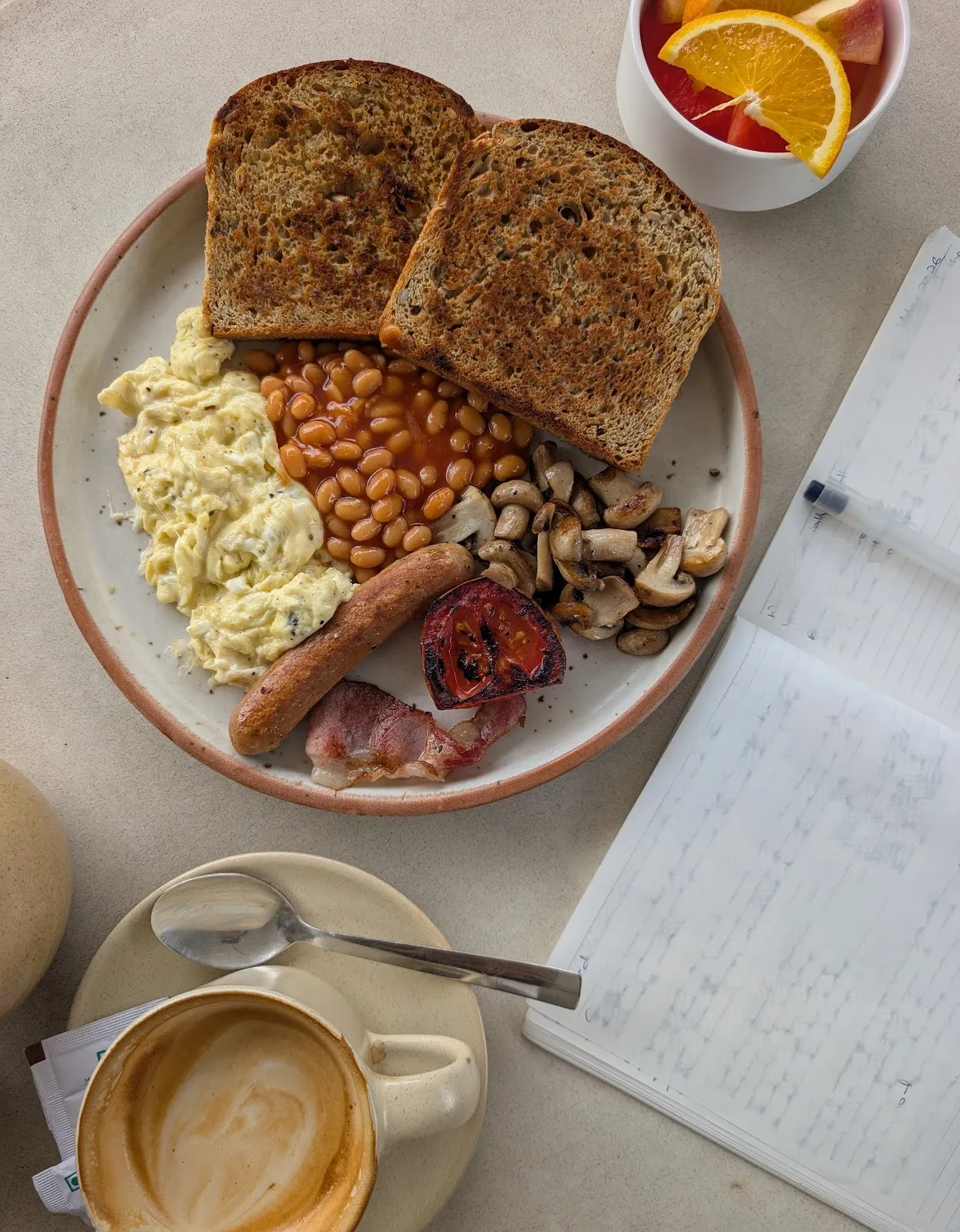 A full breakfast spread with toast, scrambled eggs, beans, mushrooms and coffee